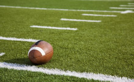 A football on a green field with white lines