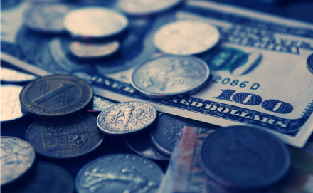 A close up of American currency including coins and a one hundred dollar bill